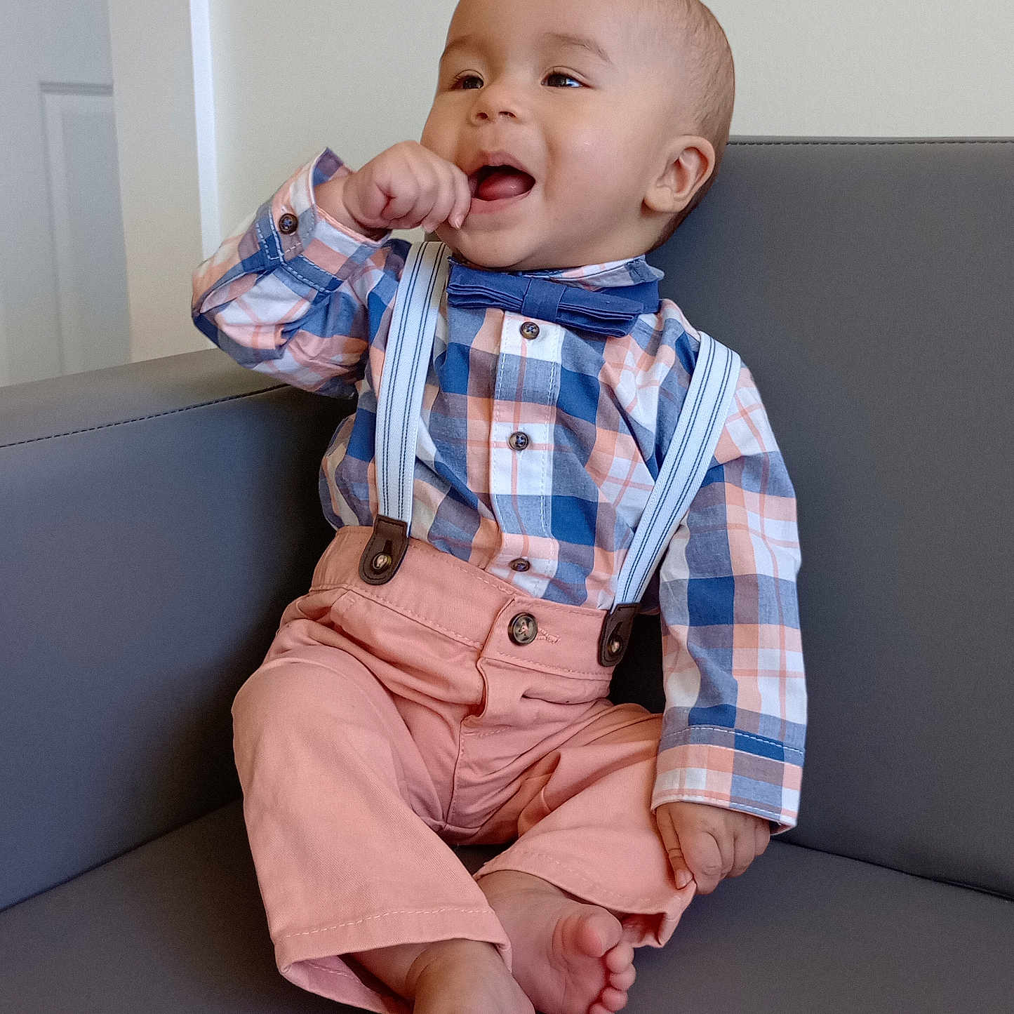 Gracen is registered to the contest to win money with this photo: baby, barefoot, bow_tie, boy, casual, child, couch, cute, furniture, hand_to_mouth, happy, indoor, infant, light_background, pink_pants, plaid_shirt, portrait, sitting, smiling, suspenders