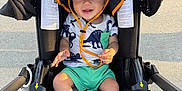Gracen joined the competition — help win amazing prizes! baby, child, stroller, hat, sunhat, socks, shorts, shirt, dinosaur_pattern, smiling, happy, outdoor, pavement, footwear, black_stroller, seat, sunlight, infant, person, cute