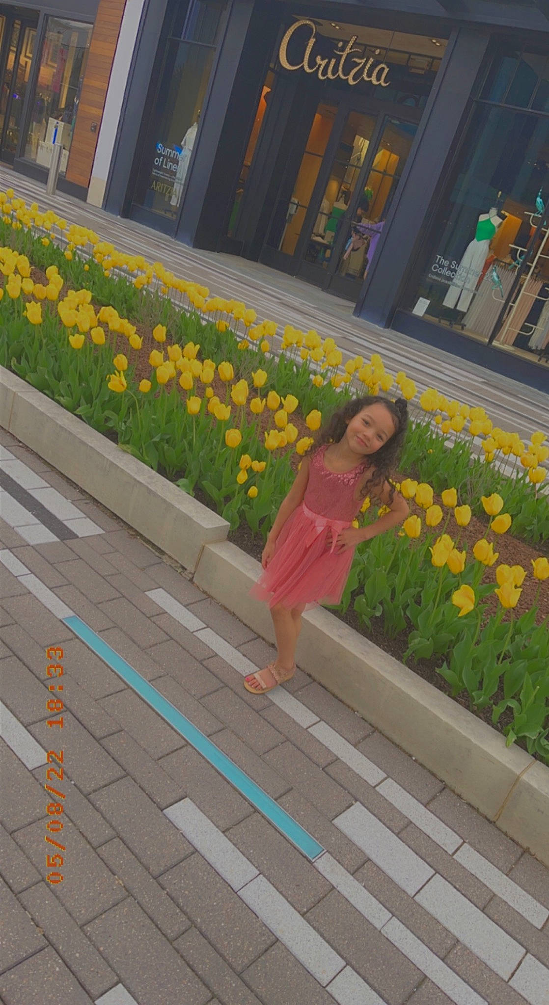 Arianna Warren is registered to the contest to win money with this photo: asphalt, botany, dress, flooring, flower, fun, grass, human_leg, joy, leisure, line, orange, pattern, person, petal, pink, plant, road_surface, sidewalk, textile