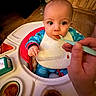 baby, baby_food, bib, child, cute, expression, face, feeding, food, hand, high_chair, home, indoor, infant, onesie, person, seat, spoon, table, wooden_floor