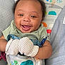 Zyir is registered to the contest to win money with this photo: baby, smiling, mittens, baby_seat, turtle, colorful, happy, infant, clothing, cute, face, child, person, seat_belt, patterned_background, playful, comfort, portrait, young, indoor