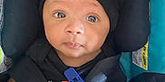 Zyir joined the competition — help win amazing prizes! baby, infant, car_seat, black_hat, mittens, blanket, seatbelt, child, portrait, cute, young, indoor, clothing, face, headwear, safety, seated, person, expression, closeup