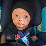 baby, infant, car_seat, black_hat, mittens, blanket, seatbelt, child, portrait, cute, young, indoor, clothing, face, headwear, safety, seated, person, expression, closeup