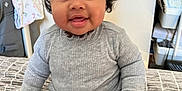 Leila is registered to the contest to win money with this photo: accessories, baby, bodypart, clothing, dress, face, finger, hand, happy, head, knitwear, longsleeve, pants, person, photography, portrait, sitting, sleeve, smile, sweater