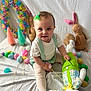 Evelynn is registered to the contest to win money with this photo: baby, child, easter, plush_toy, bunny, eggs, pastel_colors, green_bow, white_background, festive, soft_toys, cone_decorations, holiday, cute, smiling, sitting, cloth, toy, celebration, indoor