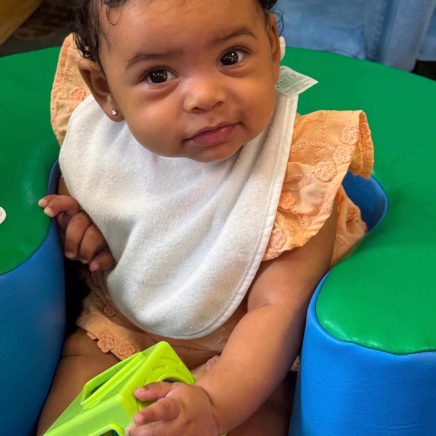 Carrera joined the competition — help win amazing prizes! baby, bib, bow, child, curly_hair, cute, earring, eyes, face, green_toy, hand, indoor, infant, padded_seat, peach_dress, play, portrait, seat, smile, toy
