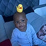 Ameileana joined the competition — help win amazing prizes! baby, child, rubber_duck, head, blue_outfit, bed, pillow, blanket, indoor, cute, smile, person, plush_headboard, infant, soft_lighting, toy, seated, cozy, home, curious
