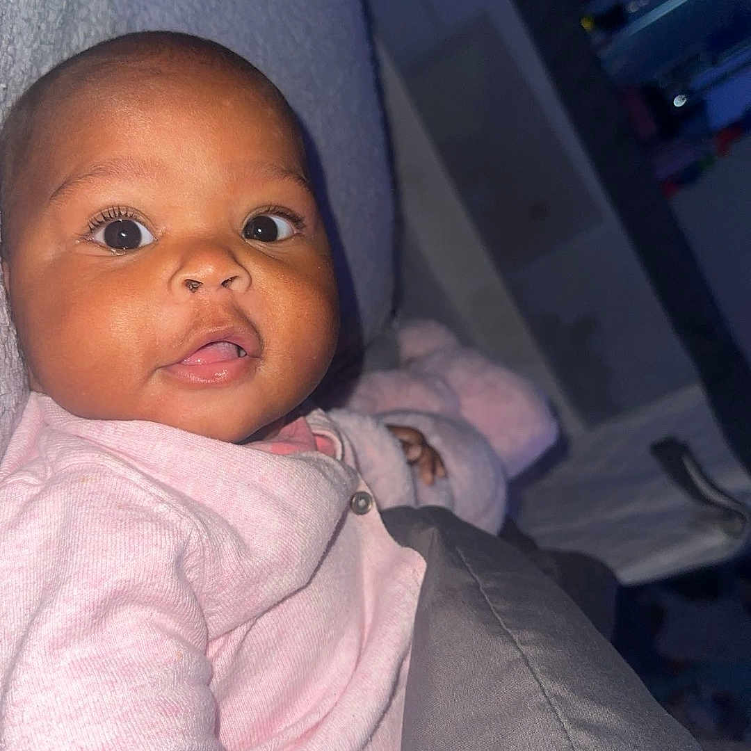 Ameileana is registered to the contest to win money with this photo: baby, blanket, child, closeup, cozy, cute, expression, eyes, face, home, indoor, infant, person, pink_clothing, portrait, sitting, sleepwear, soft_lighting, warm, young_child