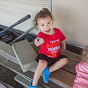 Elyis joined the competition — help win amazing prizes! bench, blue_crocs, casual_clothing, child, concrete_block, curly_hair, fun, garden, happy, outdoor, person, playful, red_shirt, rock, sitting, smiling, toddler, tool, wooden_steps, young_child