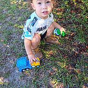 Elyis joined the competition — help win amazing prizes! brown_shoes, casual, child, curly_hair, daylight, expression, grass, greenery, nature, outdoor, person, playing, shadows, shorts, sunlight, toddler, toy, toy_truck, tshirt, young_child