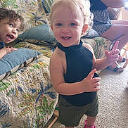 Alyiah joined the competition — help win amazing prizes! adult, barefoot, black_top, carpet, child, couch, curly_hair, floral_pattern, furniture, happy, home, indoor, person, pillow, pink_croc, playful, seated, shorts, smile, toddler