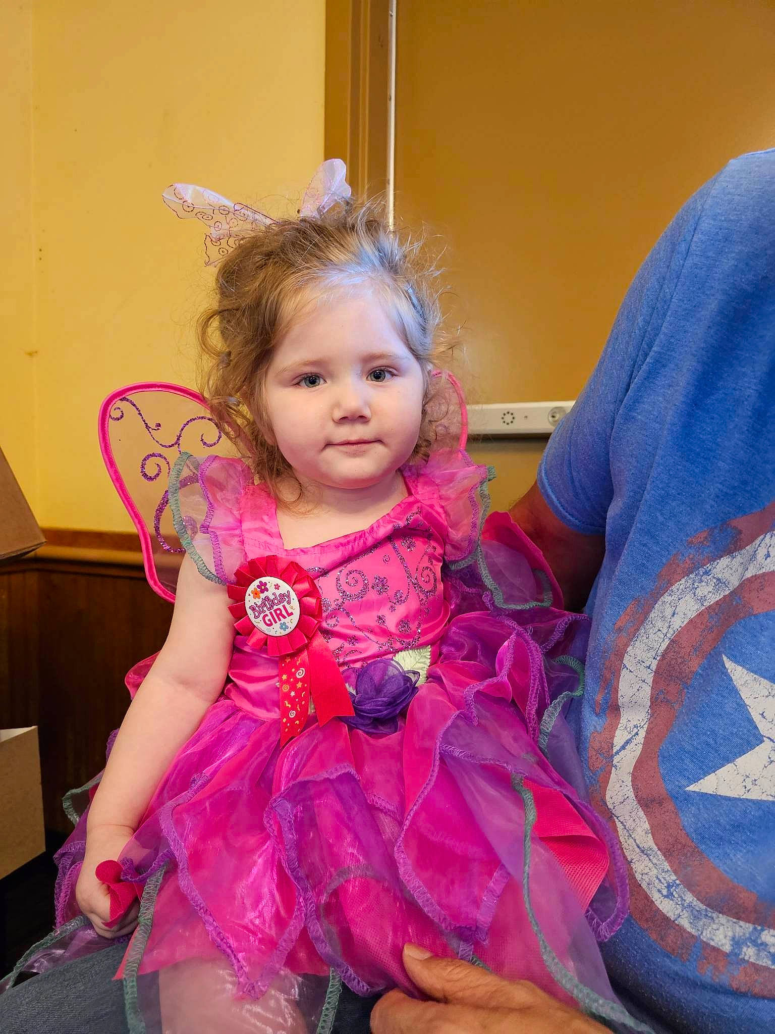 Amirah is registered to the contest to win money with this photo: baby_toddler_clothing, chair, child, dress, embellishment, event, fashion_accessory, formal_wear, fun, hair_accessory, hairstyle, happy, headpiece, iris, magenta, person, pink, purple, sitting, smile