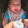 baby, bib, bottle, car_seat, clothing, eyes, fabric, feeding_bottle, foot, hand, happy, infant, mouth_open, person, portrait, seat, smiling, stroller_canopy, sunlight, warning_label