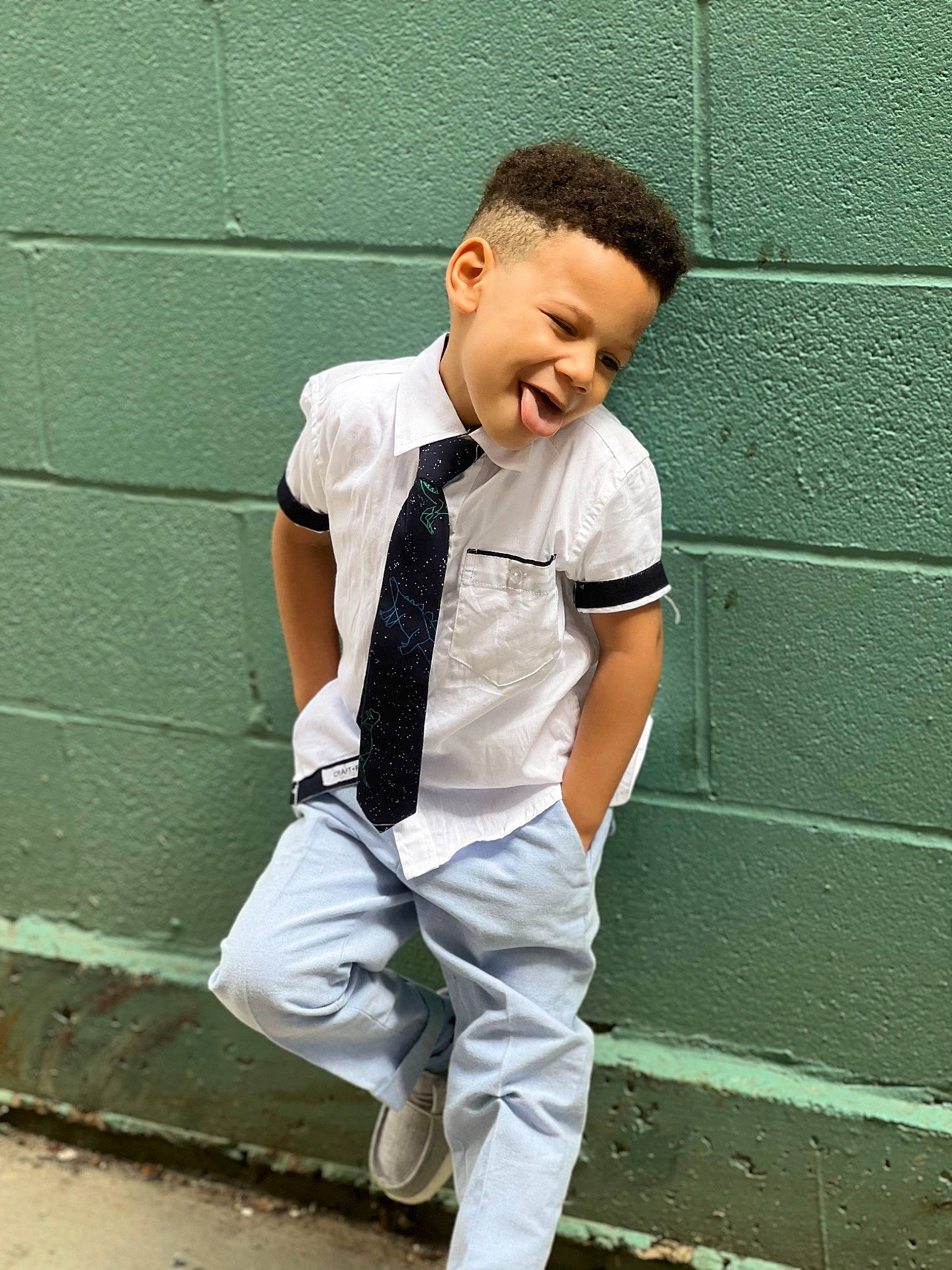 Jaquavon is registered to the contest to win money with this photo: child, collar, dress_shirt, elbow, formal_wear, gesture, hair, happy, human_leg, knee, neck, pattern, person, sitting, sleeve, sportswear, street_fashion, t_shirt, thigh, waist