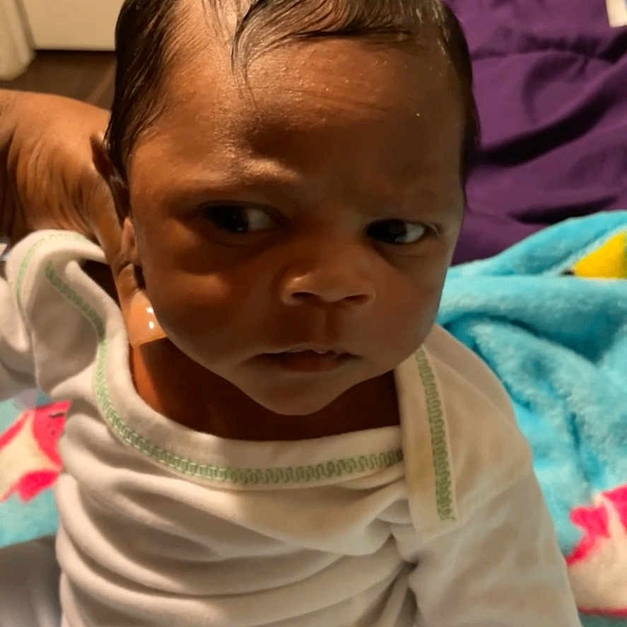 Jairus Wright is registered to the contest to win money with this photo: baby, bedroom, blanket, child, colorful_blanket, cute, face, furniture, head, human, indoor, infant, mitten, person, portrait, serious_expression, sitting, towels, white_clothing, young_child
