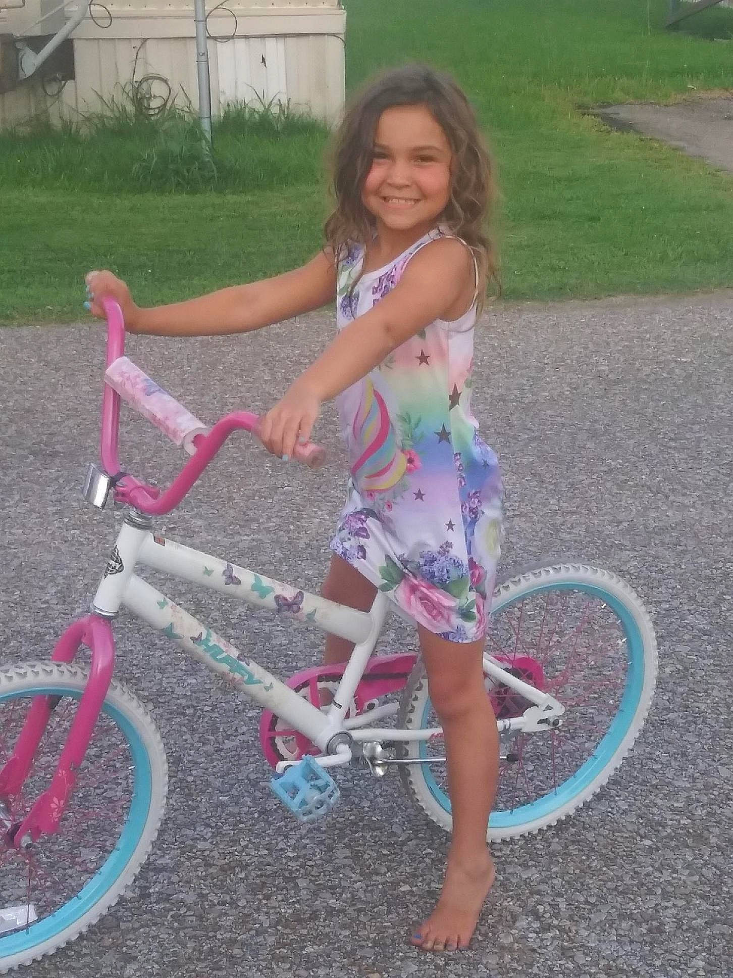Brittney is registered to the contest to win money with this photo: automotive_tire, bicycle, bicycle_accessory, bicycle_fork, bicycle_frame, bicycle_handlebar, bicycle_part, bicycle_saddle, bicycle_tire, bicycle_wheel, bicycle_wheel_rim, bicycles_equipment_and_supplies, crankset, grass, joy, person, pink, recreation, smile, spoke