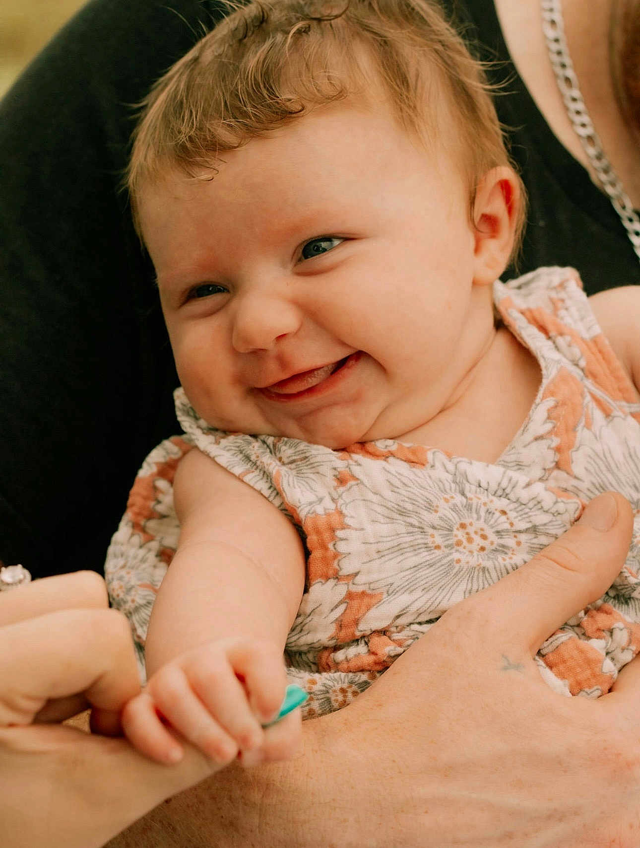 Ivory is registered to the contest to win money with this photo: baby, child, smiling, hand, holding, finger, curly_hair, dress, floral_pattern, portrait, cute, happy, skin, adult_hand, closeup, person, infant, playful, expression, warm