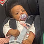 Neyla a rejoint le concours — aidez-le/la à gagner de superbes lots ! baby, car_seat, pacifier, beaded_toy, child, infant, seatbelt, pink_clothing, white_clothing, hands, face, eyes, curly_hair, safety, buckle, cute, indoor, closeup, portrait, child_safety
