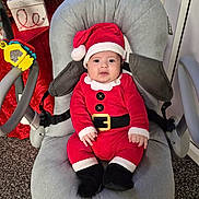 Lyam a rejoint le concours — aidez-le/la à gagner de superbes lots ! baby, santa_claus_outfit, red_clothing, baby_chair, toy, holiday, christmas, festive, gift_box, carpet, indoor, smiling, cute, child, face, hat, black_boots, seatbelt, cushion, decorations