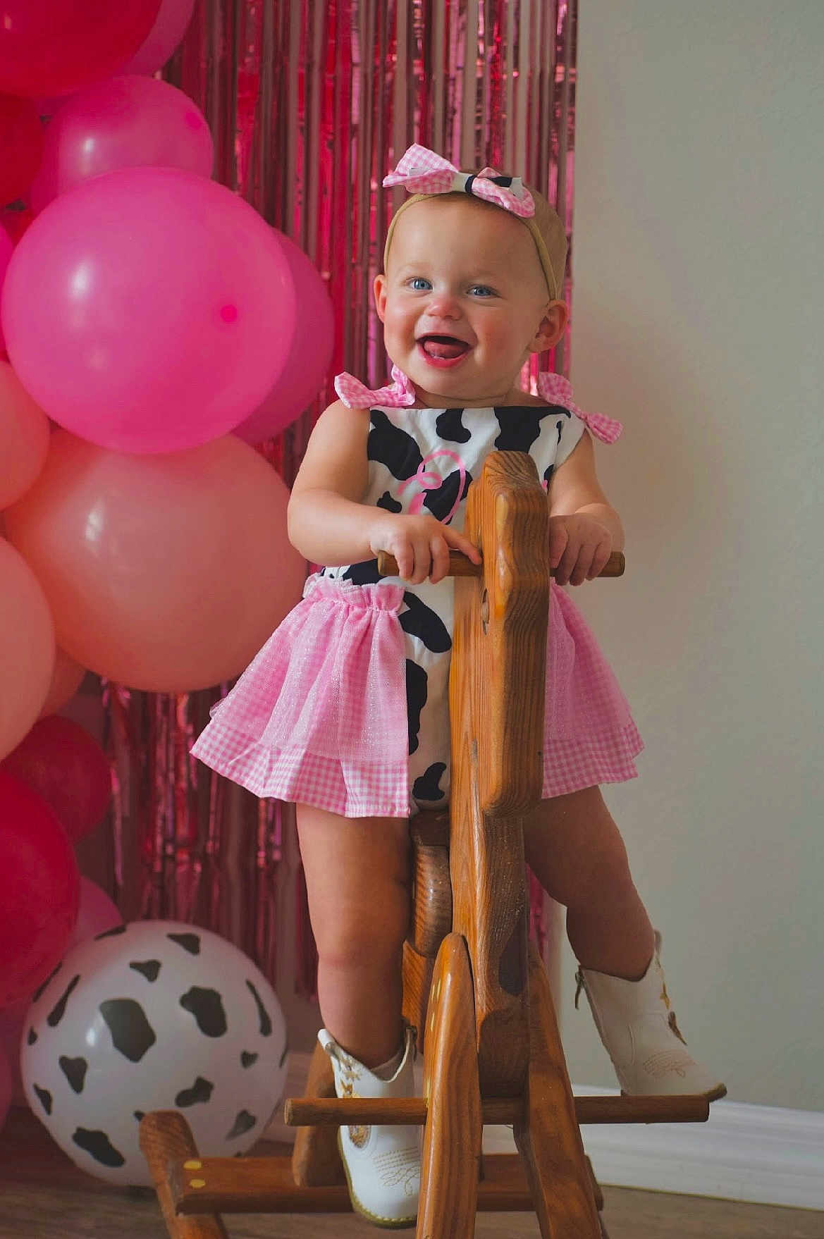 Dallas Grace is registered to the contest to win money with this photo: toddler, child, smiling, rocking_horse, wooden_toy, pink_dress, headband, cow_print, cowboy_boots, balloons, pink_balloons, party_decoration, indoor, floor, happy, girl, toy, celebration, cute, portrait