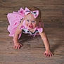 baby, child, crawling, pink_dress, bow, headband, blue_eyes, happy, floor, wood_floor, indoors, person, cute, smiling, toddler, skin, arms, fingers, clothing, portrait