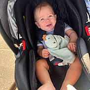 Lyham a rejoint le concours — aidez-le/la à gagner de superbes lots ! baby, car_seat, smiling, blue_eyes, plush_toy, dinosaur, striped_clothing, barefoot, outdoor, sunlight, blanket, happy, child, infant, seatbelt, person, cute, portrait, baby_toy, baby_boy