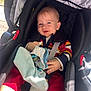 baby, child, car_seat, seatbelt, striped_sweater, red_pants, pacifier, soft_toy, blanket, smiling, blue_eyes, indoor, sunlight, comfort, infant, clothing, person, cute, happy, young