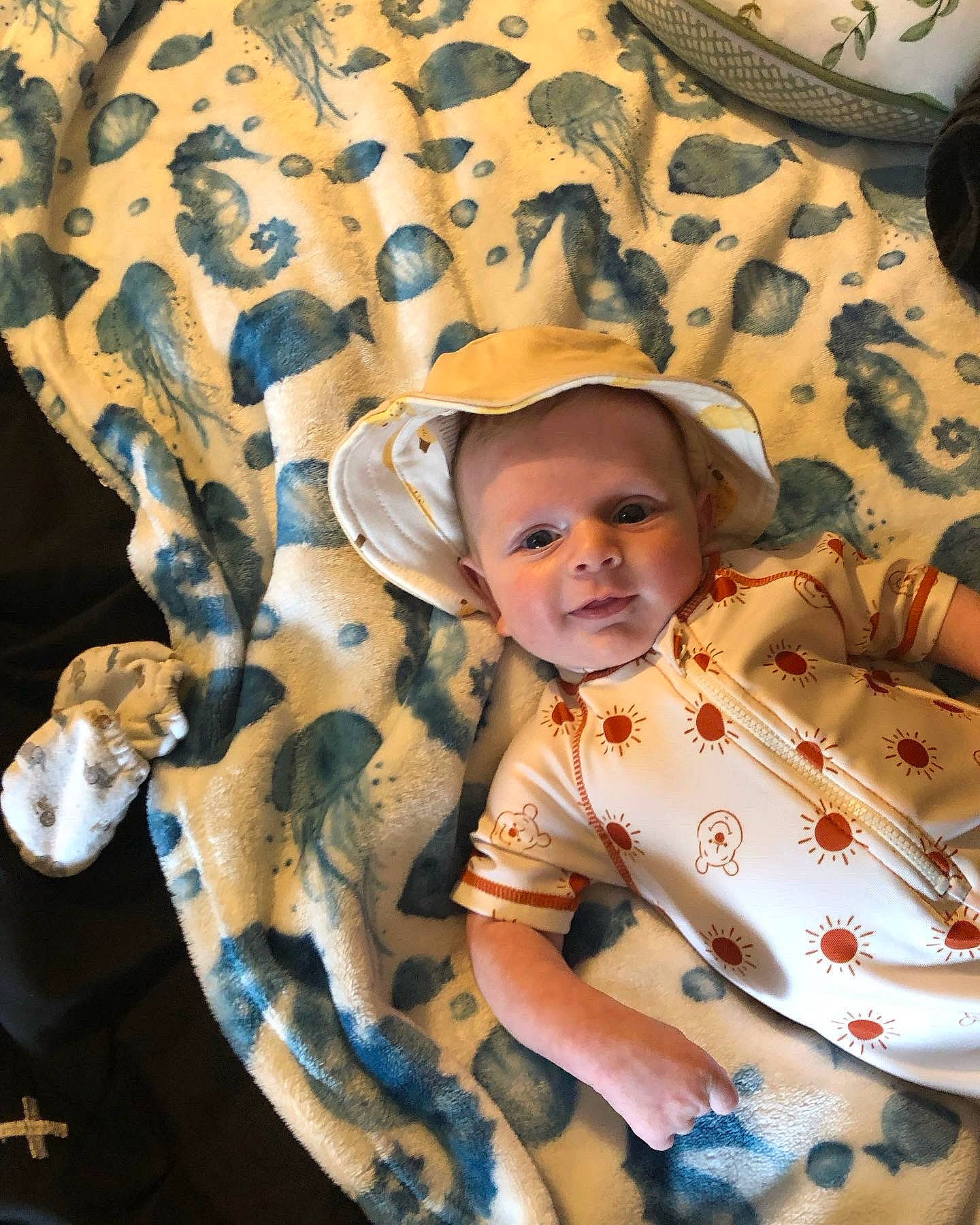 Jaxton is registered to the contest to win money with this photo: baby, baby_toddler_clothing, bedding, child, comfort, eye, fashion_accessory, fun, happy, hat, headgear, linens, pattern, person, portrait_photography, room, sitting, sleeve, sun_hat, toddler
