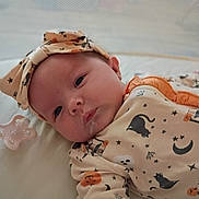Nora joined the competition — help win amazing prizes! newborn, baby, infant, child, portrait, face, eyes_open, lying_down, onesie, pajamas, headband, pacifier, bed, blanket, indoor, close_up, sleepy, calm, pumpkins, stars