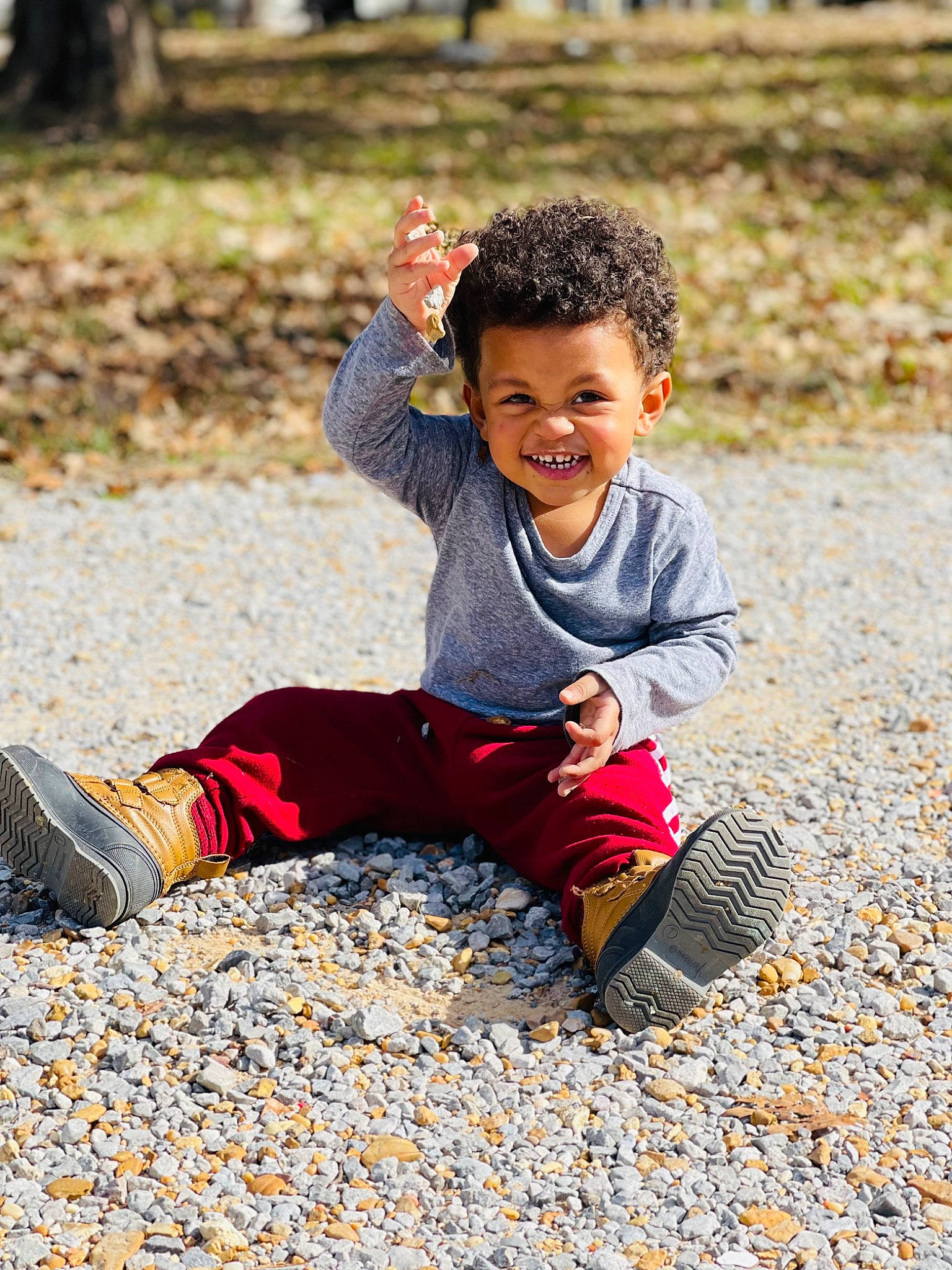 Tre is registered to the contest to win money with this photo: autumn, child, clothing, deciduous, fun, grass, happy, joy, landscape, leisure, people_in_nature, person, plant, play, portrait_photography, recreation, sitting, smile, sneakers, soil