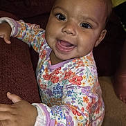 Desyah is registered to the contest to win money with this photo: baby, child, smiling, pajamas, floral, indoor, couch, fabric, hand, face, person, happy, infant, carpet, home, cute, young_child, clothing, portrait, bright