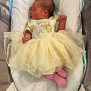 Alora joined the competition — help win amazing prizes! newborn, baby, sleeping, yellow_dress, tutu, pink_socks, bassinet, blanket, cozy, infant, cute, resting, indoors, portrait, child, soft_lighting, peaceful, clothing, fabric, mesh_sides