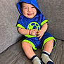 baby, child, smiling, hoodie, blue_clothing, socks, couch, indoor, portrait, cute, happy, infant, seated, young_child, socked_feet, sporty_outfit, neon_green, casual, comfortable, playful