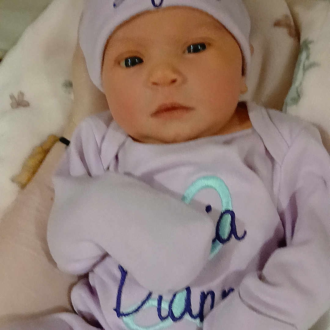 Lycia joined the competition — help win amazing prizes! baby, infant, hat, bow, clothing, blanket, person, face, eyes, mouth, cute, newborn, purple, soft, sleepwear, child, portrait, indoors, resting, young