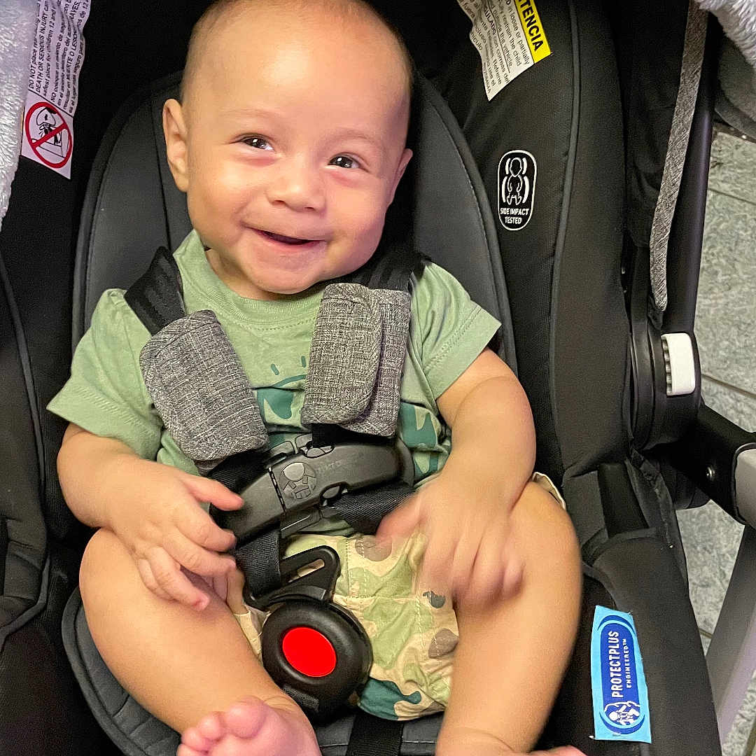 Noah is registered to the contest to win money with this photo: accessories, baby, bodypart, car, electronics, face, finger, gun, hand, happy, head, person, photography, portrait, smile, strap, stroller, transportation, vehicle, weapon