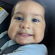 Miguel is registered to the contest to win money with this photo: baby, child, smile, face, car_seat, seatbelt, clothing, eyebrows, cheeks, skin, person, infant, cute, portrait, young, head, indoors, happy, closeup, baby_clothes