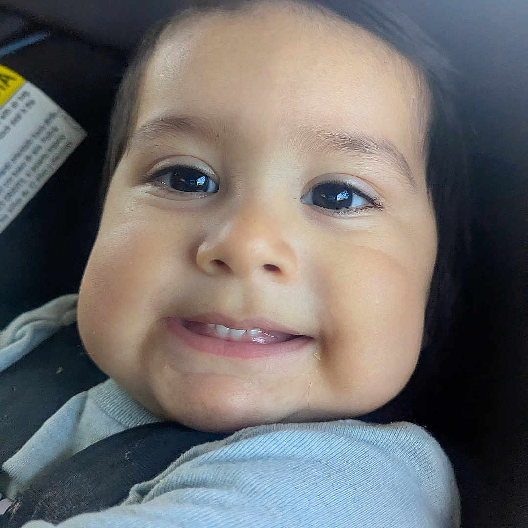 Miguel is registered to the contest to win money with this photo: baby, baby_clothes, car_seat, cheeks, child, closeup, clothing, cute, eyebrows, face, happy, head, indoors, infant, person, portrait, seatbelt, skin, smile, young