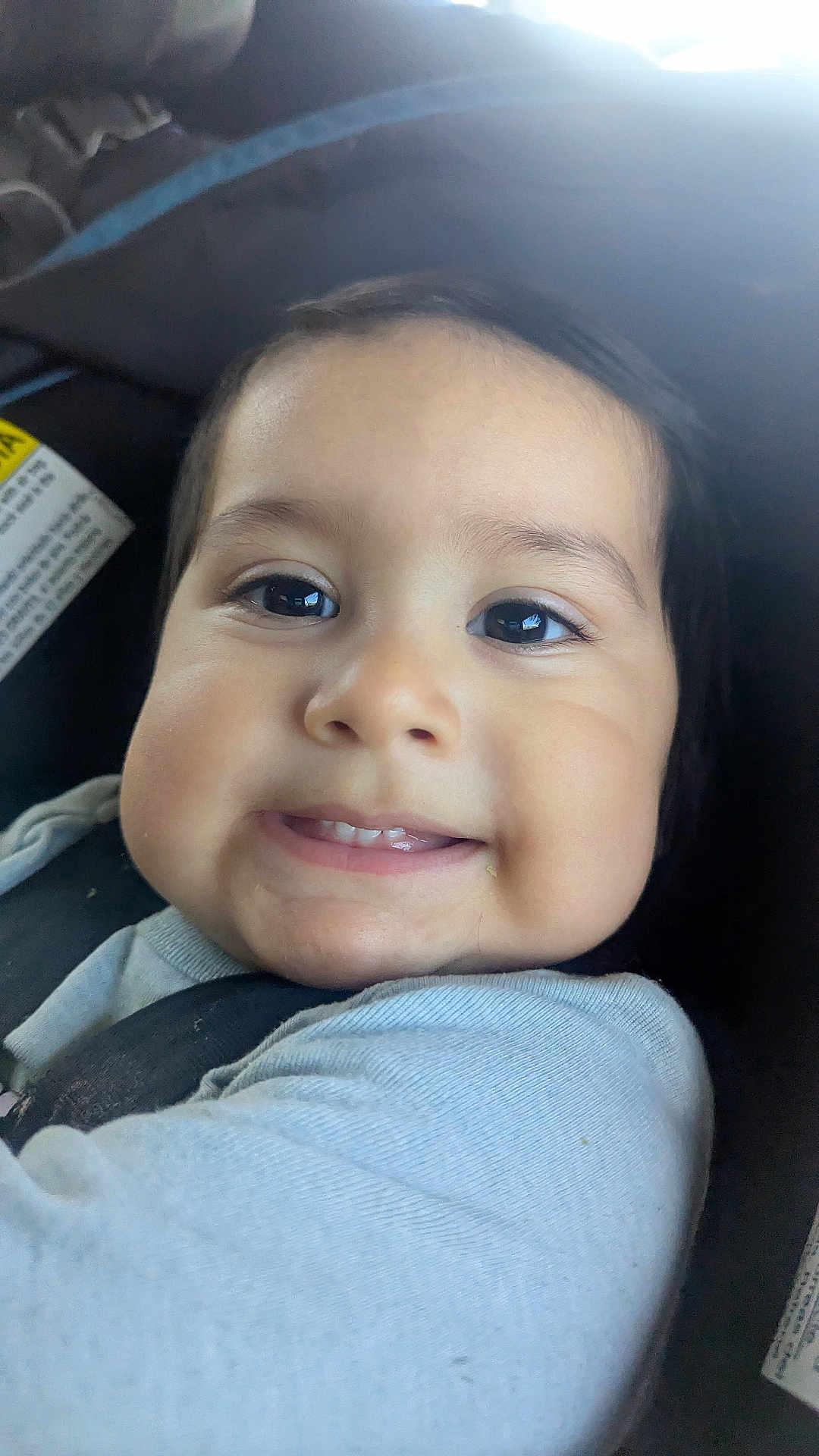 Miguel is registered to the contest to win money with this photo: baby, child, smile, face, car_seat, seatbelt, clothing, eyebrows, cheeks, skin, person, infant, cute, portrait, young, head, indoors, happy, closeup, baby_clothes