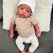 Kenai joined the competition — help win amazing prizes! adorable, baby, chain, child, couch, cozy, cute, hat, indoor, infant, looking_at_camera, neutral_clothing, pillow, portrait, relaxed, sitting, skin_tone, small_feet, small_hands, soft_texture