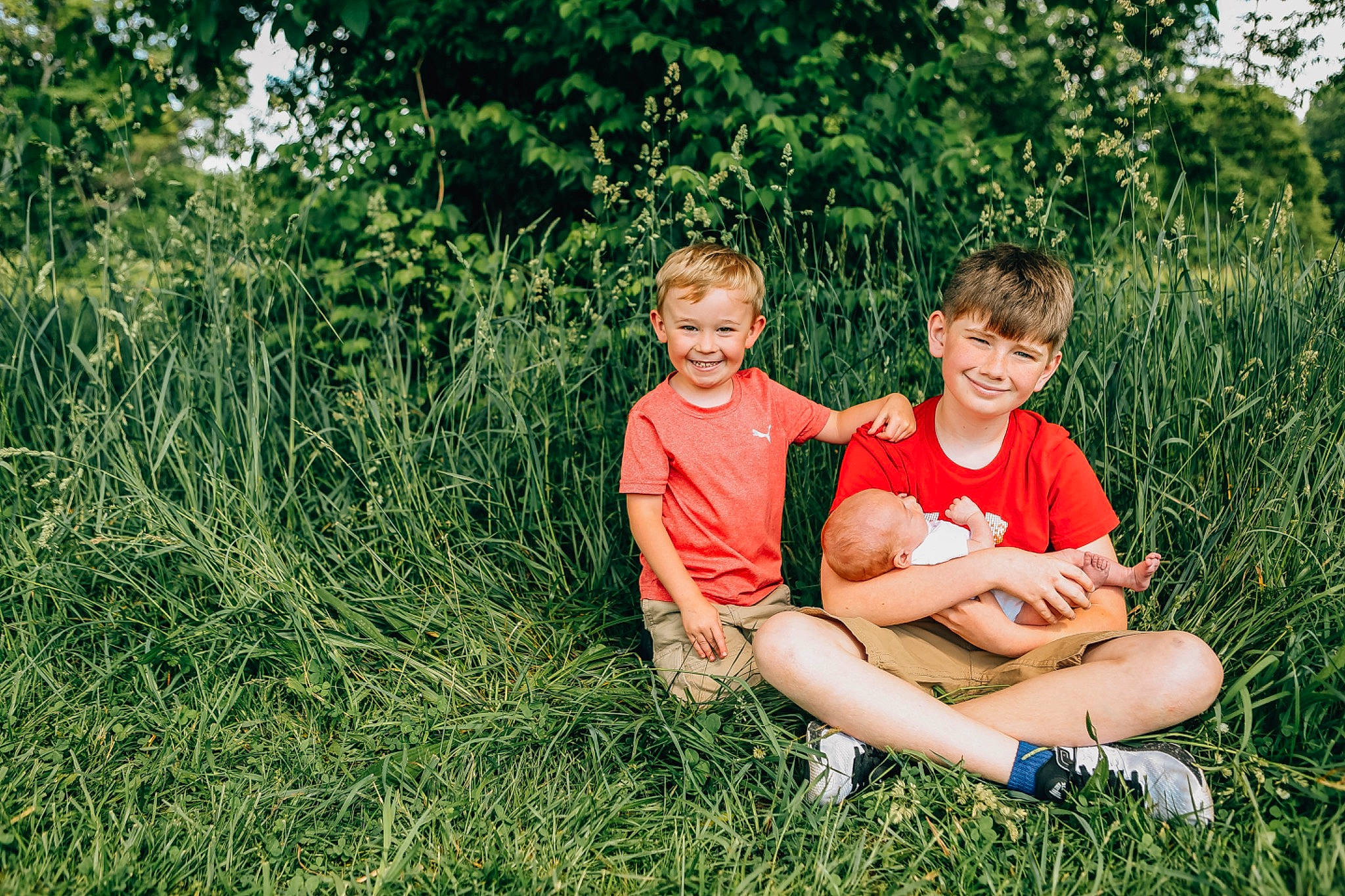Benson is registered to the contest to win money with this photo: event, grass, grassland, happy, joy, landscape, lap, lawn, leg, leisure, meadow, natural_landscape, people_in_nature, person, plant, prairie, shorts, sitting, smile, t_shirt