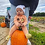 baby, pumpkin, field, outdoor, child, hat, person, jeans, hoodie, cloudy_sky, plant, grass, fall, autumn, nature, footwear, shoes, cute, sitting, pumpkin_patch