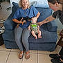 Dory joined the competition — help win amazing prizes! woman, baby, dog, couch, indoor, smiling, pacifier, blue_clothing, leggings, flip_flops, tattoo, tile_floor, glasses, blanket, hand, sitting, interaction, pet, family, friendly