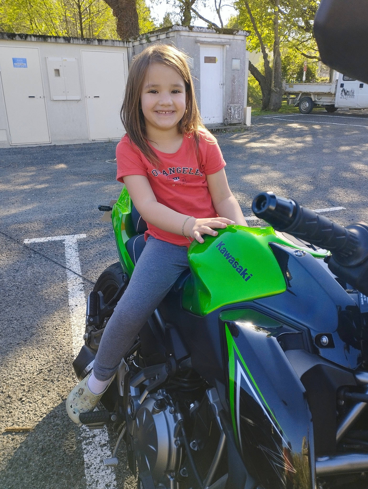 Shayna a rejoint le concours — aidez-le/la à gagner de superbes lots ! alloy_wheel, automotive_design, automotive_exterior, automotive_lighting, automotive_tire, automotive_wheel_system, fender, fuel_tank, grass, headlamp, joy, motor_vehicle, motorcycle, motorcycle_accessories, person, public_space, rim, smile, tire, tree