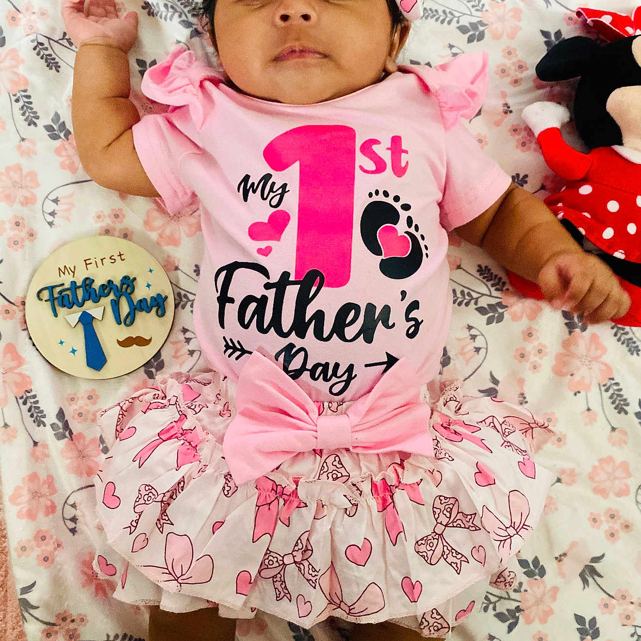 Meisha joined the competition — help win amazing prizes! baby, infant, child, pink_outfit, headband, plush_toy, minnie_mouse, floral_blanket, celebration, first_fathers_day, wooden_plaque, smiling, cute, tutu_skirt, lying_down, indoors, adorable, portrait, clothing, happy