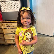 Rae Bates is registered to the contest to win money with this photo: belle, calendar, carpet, child, curly_hair, cute, denim_shorts, disney, door, dresser, girl, happy, home, indoor, person, portrait, smiling, standing, yellow_bows, yellow_shirt