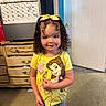 belle, calendar, carpet, child, curly_hair, cute, denim_shorts, disney, door, dresser, girl, happy, home, indoor, person, portrait, smiling, standing, yellow_bows, yellow_shirt