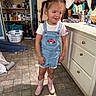 cabinet, casual, child, cleaning_supplies, clothing, denim_overalls, door, floor_tiles, girl, hair_ties, household, indoor, laundry_basket, laundry_room, mirror, pigtails, pink_boots, smile, standing, vacuum_cleaner