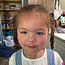 Rae Bates joined the competition — help win amazing prizes! blue_eyes, braids, child, closeup, curly_hair, denim_overalls, face, girl, hair, household_items, indoor, laundry_basket, messy_room, person, portrait, shelves, skin, smile, white_shirt, young_child