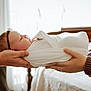 Charlotte joined the competition — help win amazing prizes! baby, newborn, swaddled, hands, bedroom, blanket, headband, sleeping, infant, people, adult_hands, soft_light, bed, white, cozy, indoor, portrait, calm, family, care