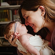 Charlotte joined the competition — help win amazing prizes! baby, woman, smile, face, headband, earrings, holding, love, affection, family, indoor, portrait, skin, closeup, person, newborn, wrapped, cuddle, happy, bookshelf